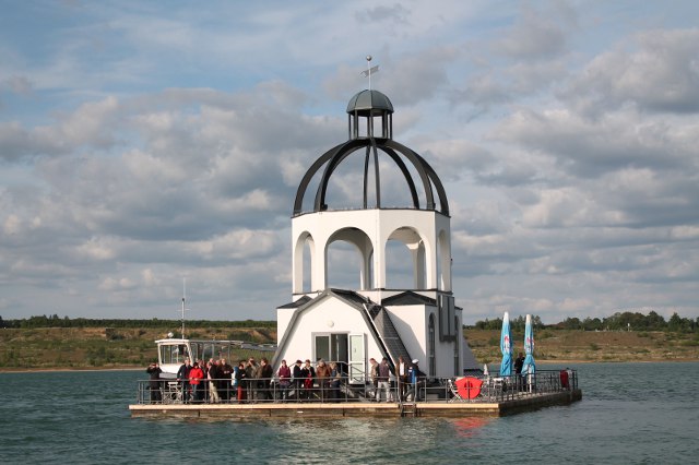 Tagungsteilnehmer auf der „Vineta“, einem schwimmenden Kunstobjekt in Anlehnung an die überbaggerte Kirche von Magdeborn, das auf dem Störmthaler See an die für die Kohlengewinnung im Tagebau Espenhain umgesiedelten Ortschaften erinnern soll